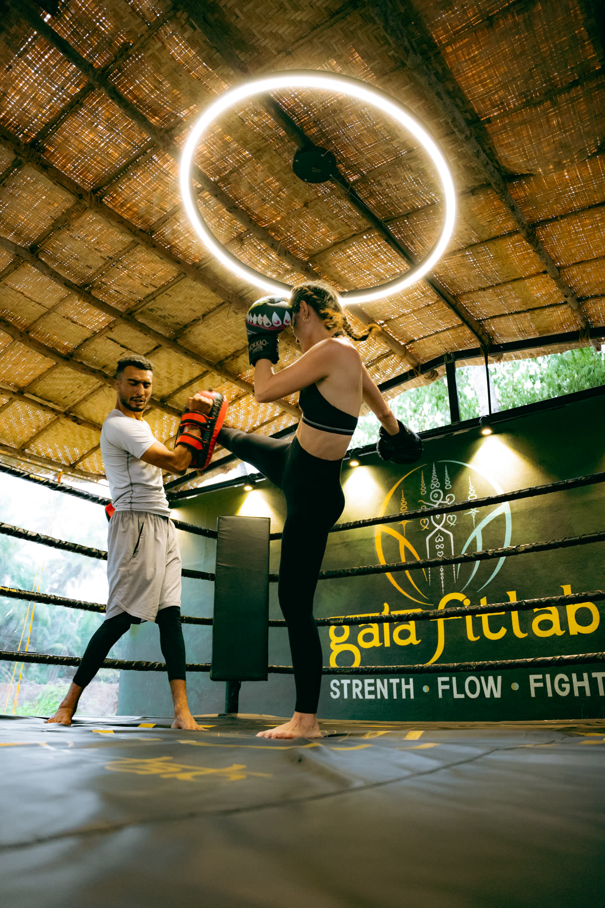 High kick pad work under the ring light at Gaia Fit Lab
