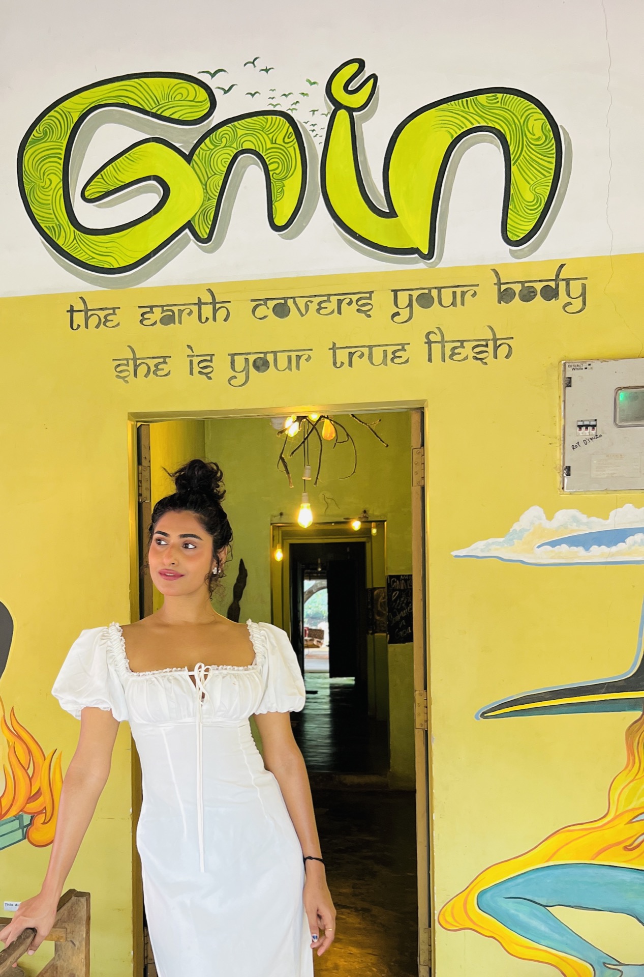 Sharo Philip — founder of Home of Gaia, standing under the Gaia mural in Morjim